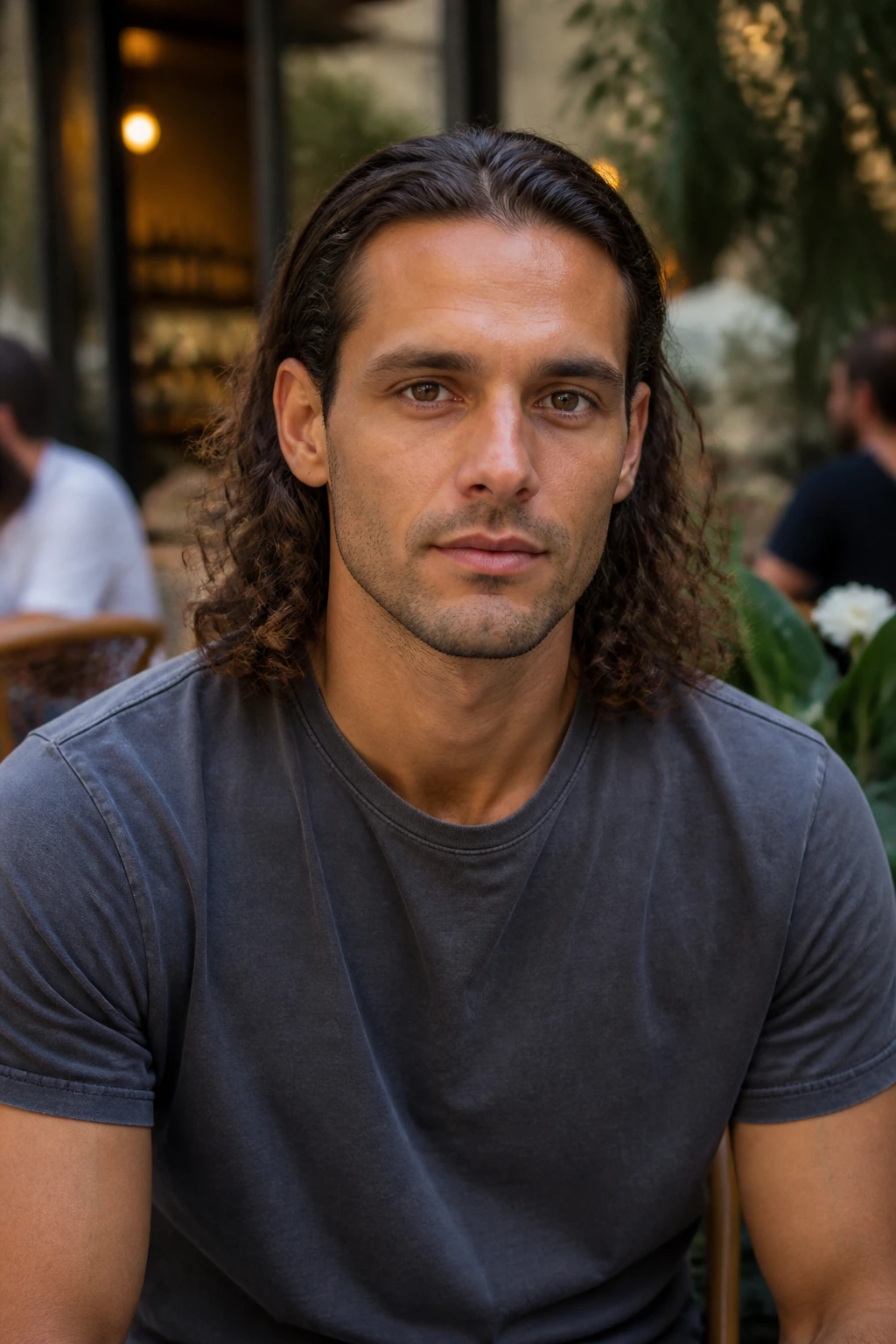 Close-up of a man with natural curls tucked behind both ears, highlighting cheekbones