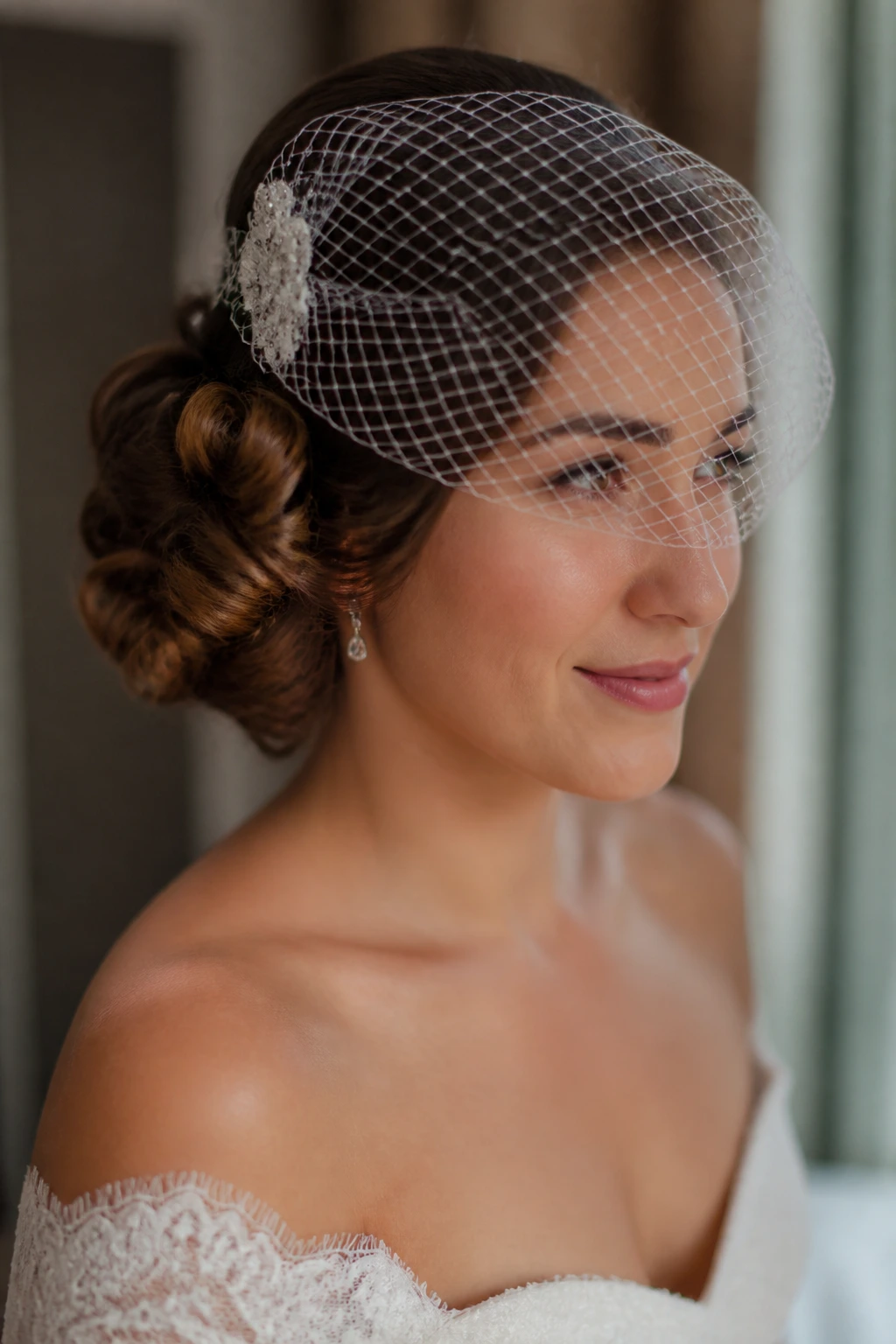 Close-up of a real bride with tucked curl roll and birdcage veil