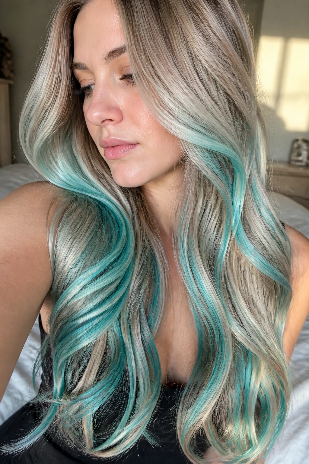 Close-up of a real woman's long hair with turquoise ribbon highlights threading through mids and ends