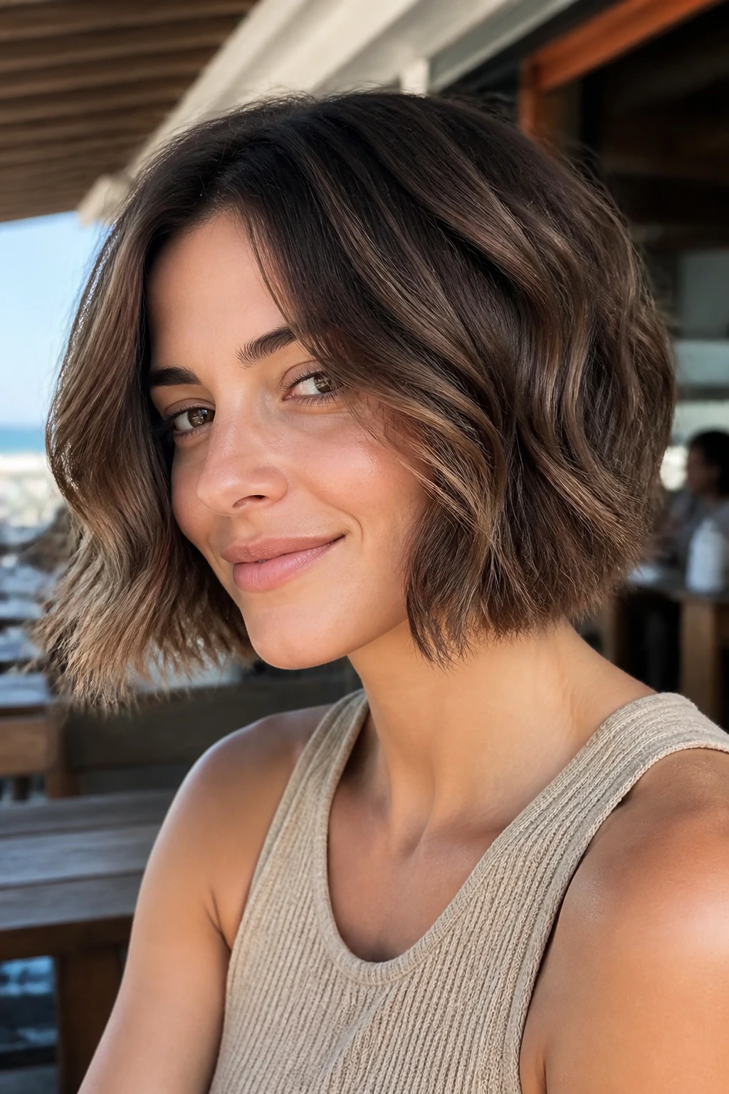 Walnut brown beachy bob with soft waves on a real person by the beach.