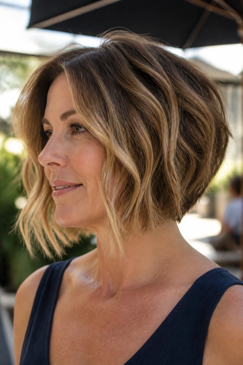 Close-up of a woman with a wavy inverted bob in daylight.