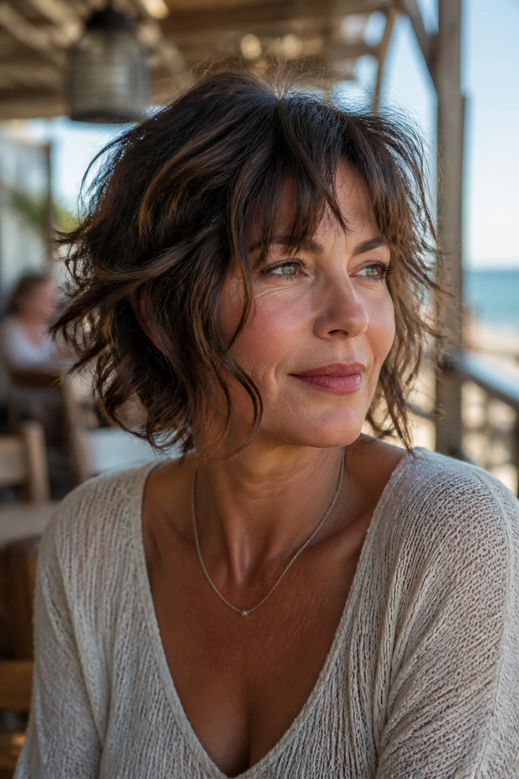 Close-up portrait of a real woman with wavy shag jaw-skimming pieces by the seaside.