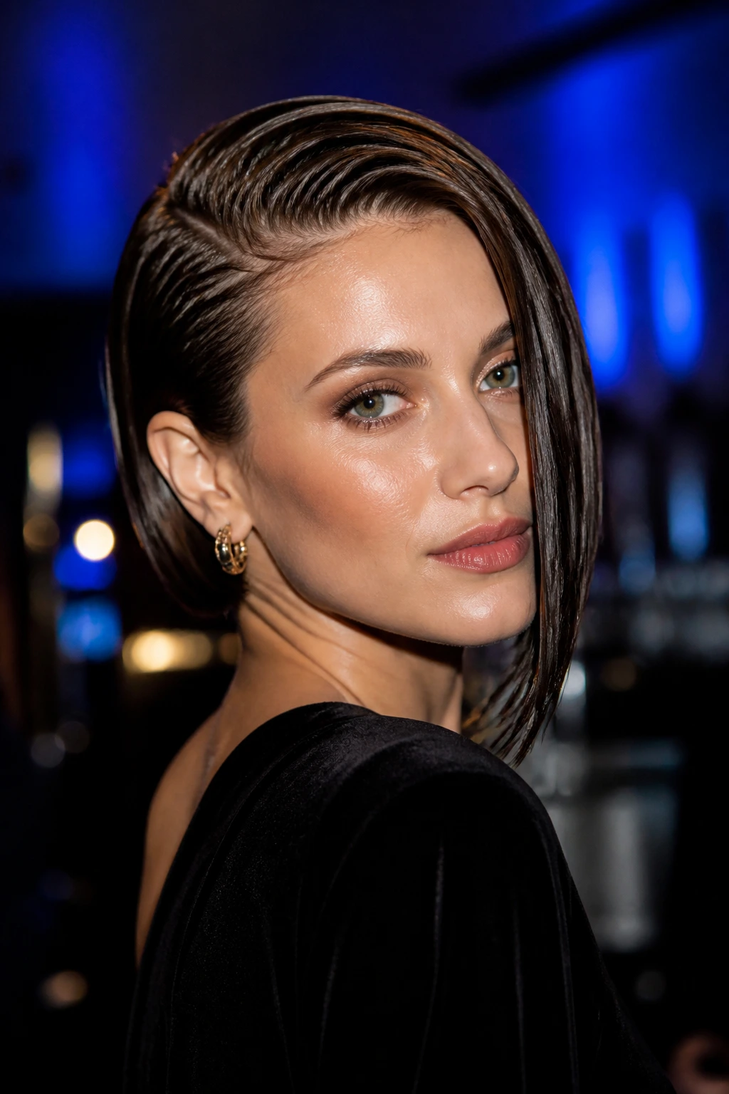 Portrait of a real woman with a wet-look asymmetrical bob under moody lighting.