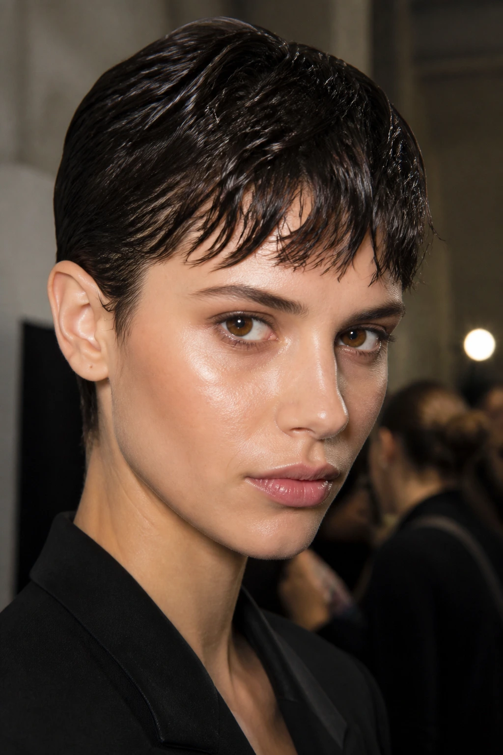 Close-up portrait of a real woman with brunette wet-look crop backstage at a fashion shoot