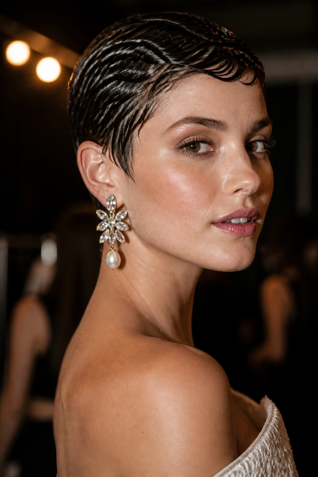 Close-up of a real woman wearing a glossy wet-look pixie with statement earrings